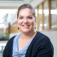 Roos de Boer, werkzaam als administrateur bij Academie Organisatie en Ontwikkeing. lichtblauw shirt, donkerblauw vest, brildragend en oorbellen