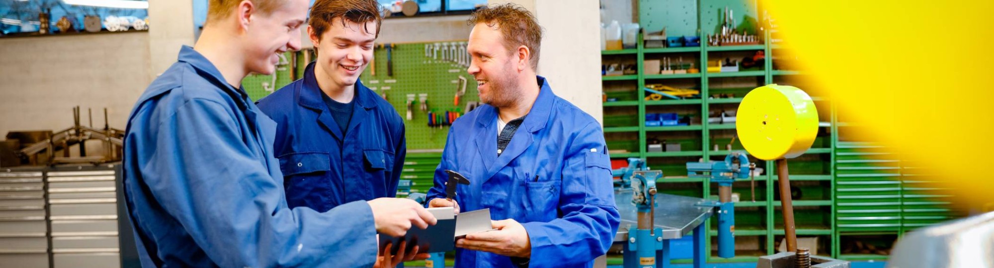 Studenten en docent in werkplaats met gereedschap