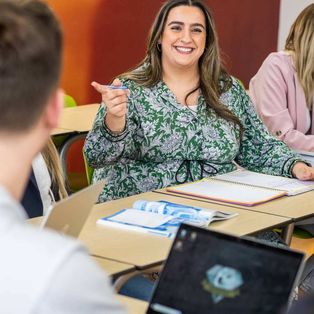 Student wijst naar iemand en lacht.