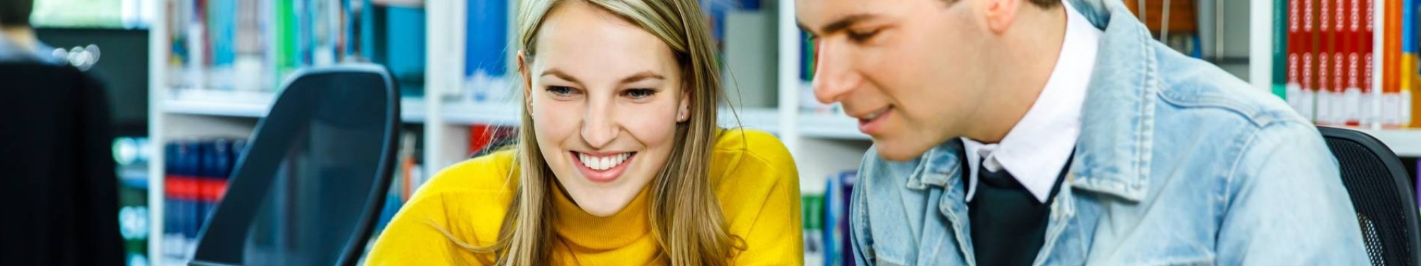 Twee HAN-studenten Leraar Nederlands werken achter één laptop in de mediatheek. 