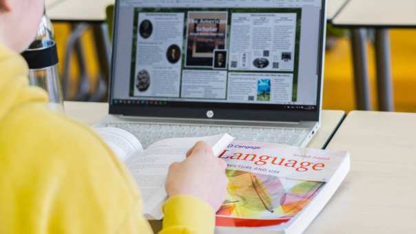 masterstudent zit met een taalboek en laptop voor haar neus