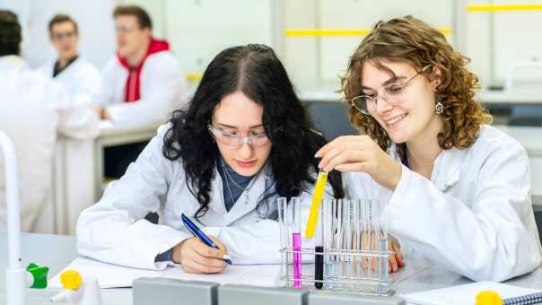 Twee studenten bekijken een vloeistof in een buisje.
