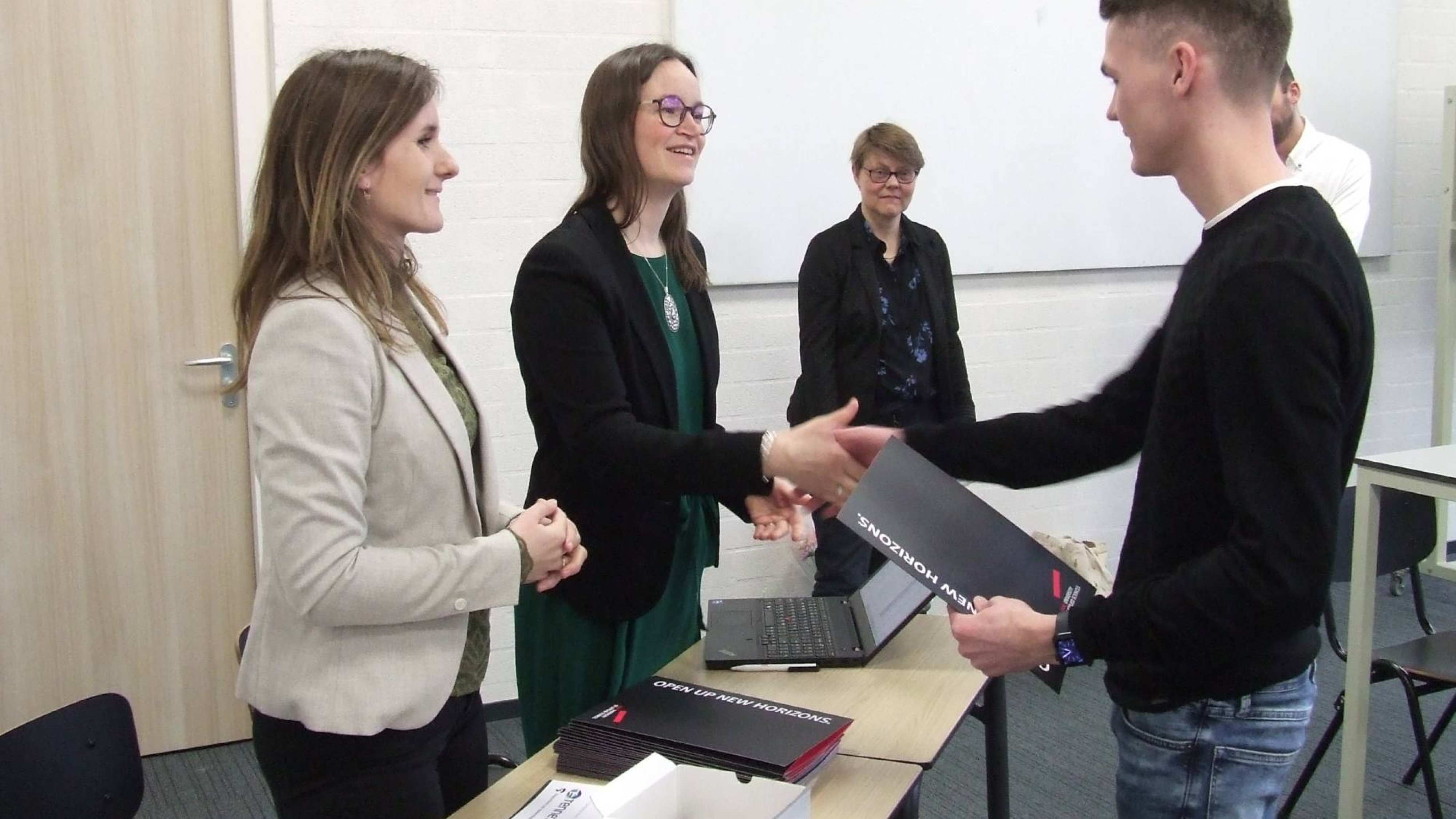 Student Dimas die in een collegezaal zijn Power Minor certificaat in ontvangst neemt.