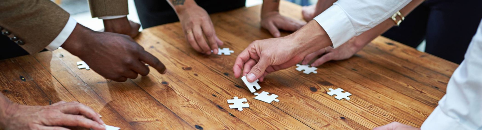 Op een vierkante houten tafel samen een puzzel leggen. Puzzelstukjes, samenwerken, seece