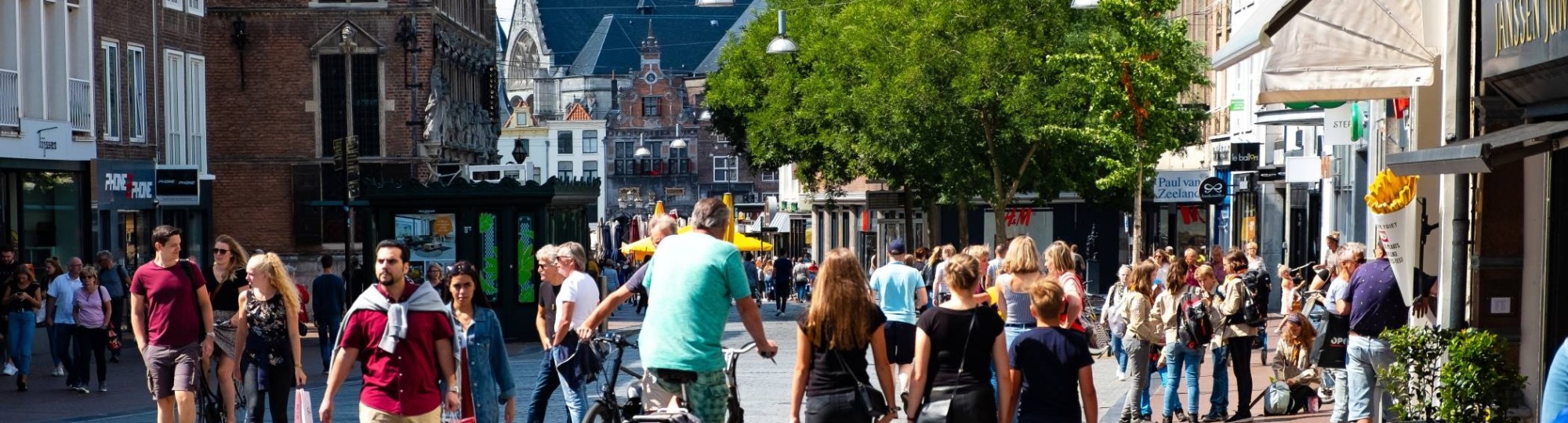 mensen in winkelstraat met kerk op achtergrond