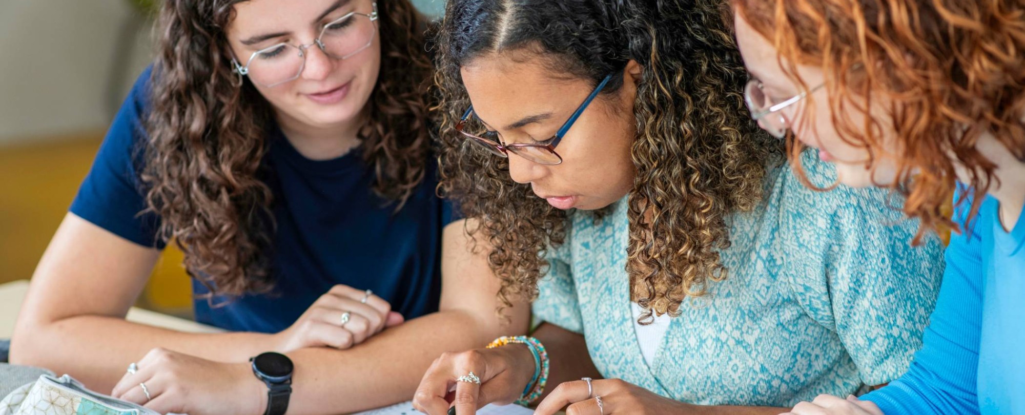 Twee studenten Leraar Wiskunde kijken toe terwijl een andere student een som intypt op de rekenmachine
