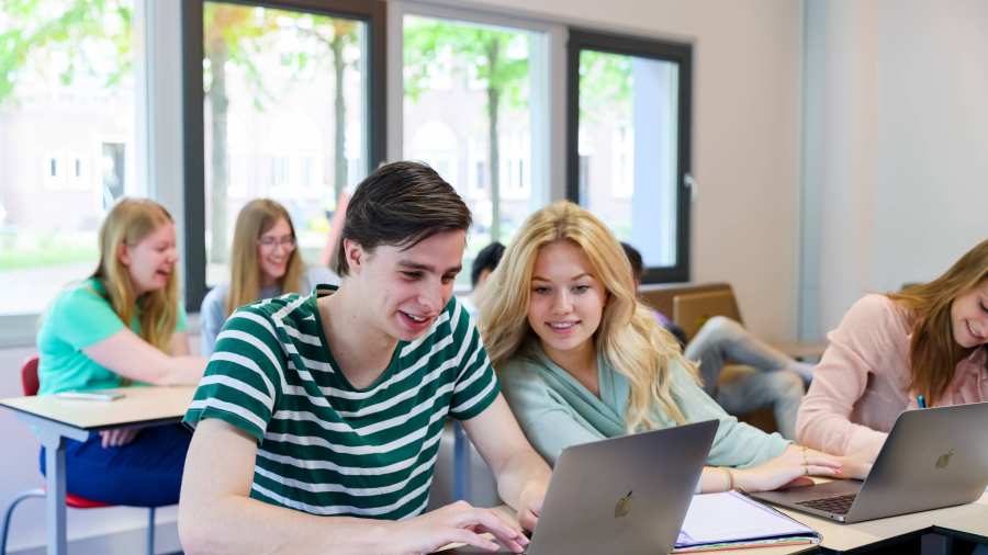 Foto Bedrijfskunde voltijd Nijmegen, klassetting, studenten samenwerken, laptops