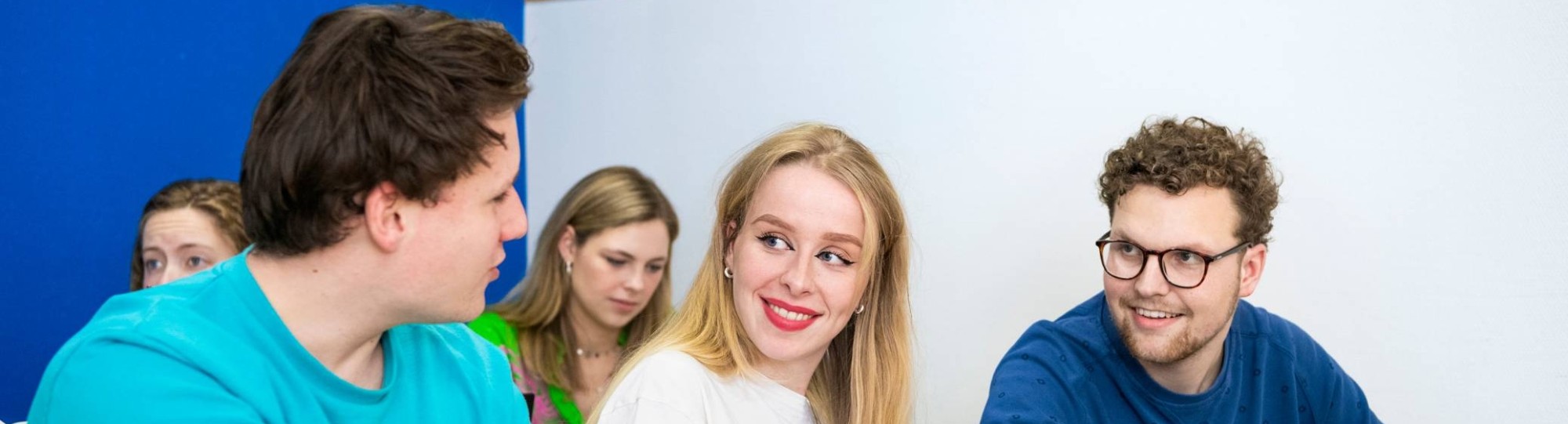 Studenten leraar Duits zitten aan een grote tafel in de kantine van het I/O gebouw en zijn aan het overleggen.