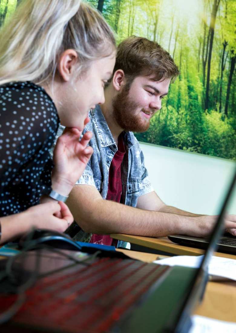 Studenten HAN Pabo Arnhem kijken bij elkaar op laptop en lachen.