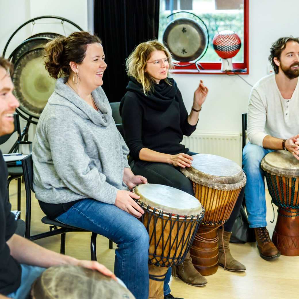 Studenten van de Master Vaktherapie maken muziek op trommels.