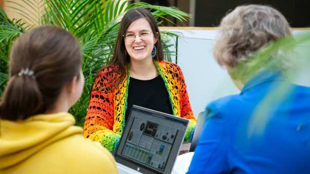 close-up lachende masterstudent die met 2 anderen aan tafel zit