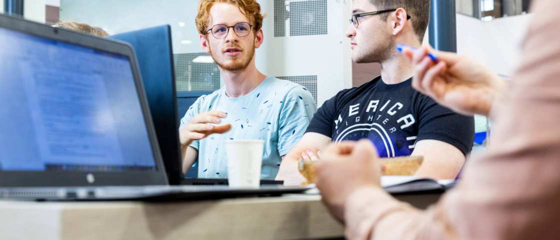 Two Mechanical Engineering students doing group work behind laptops - Werktuigbouwkunde