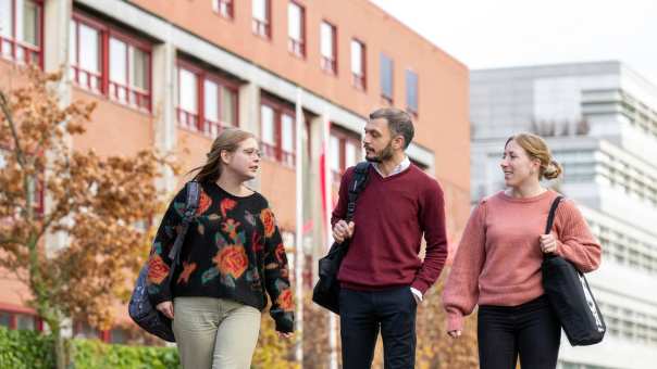 3 studenten praten en lopen buiten. 