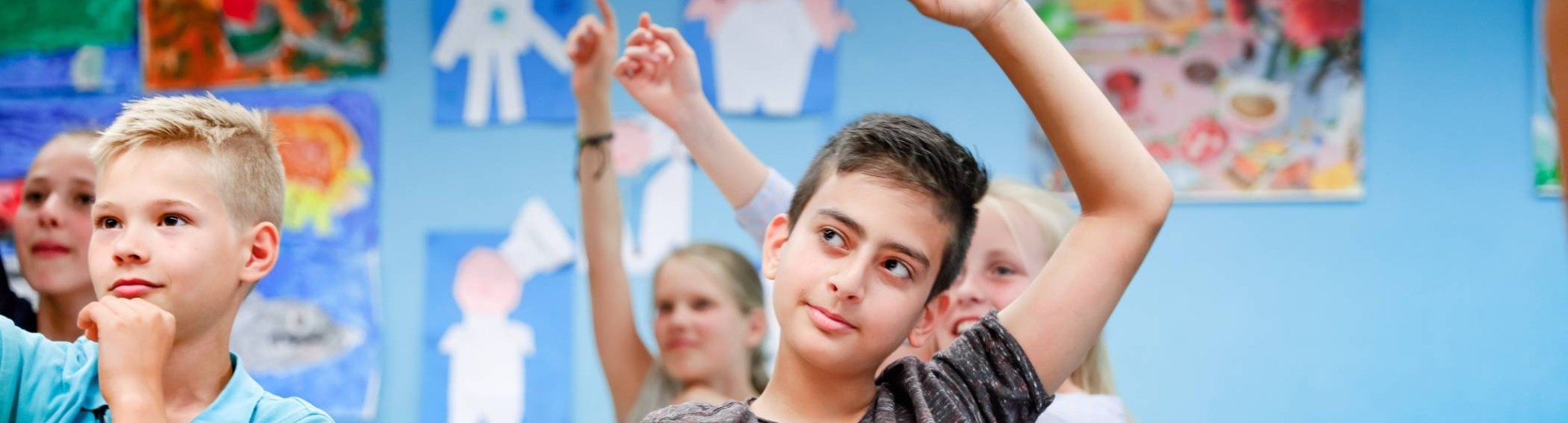 5 kinderen zitten in de klas en steken hun vinger op.