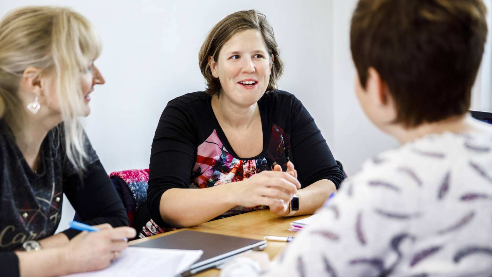 drie vrouwen overleggen een vrouw schrijft in notitieblok