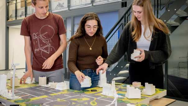 Studenten krijgen uitleg over de smart grid tafel door een docent Engineering en Automotive