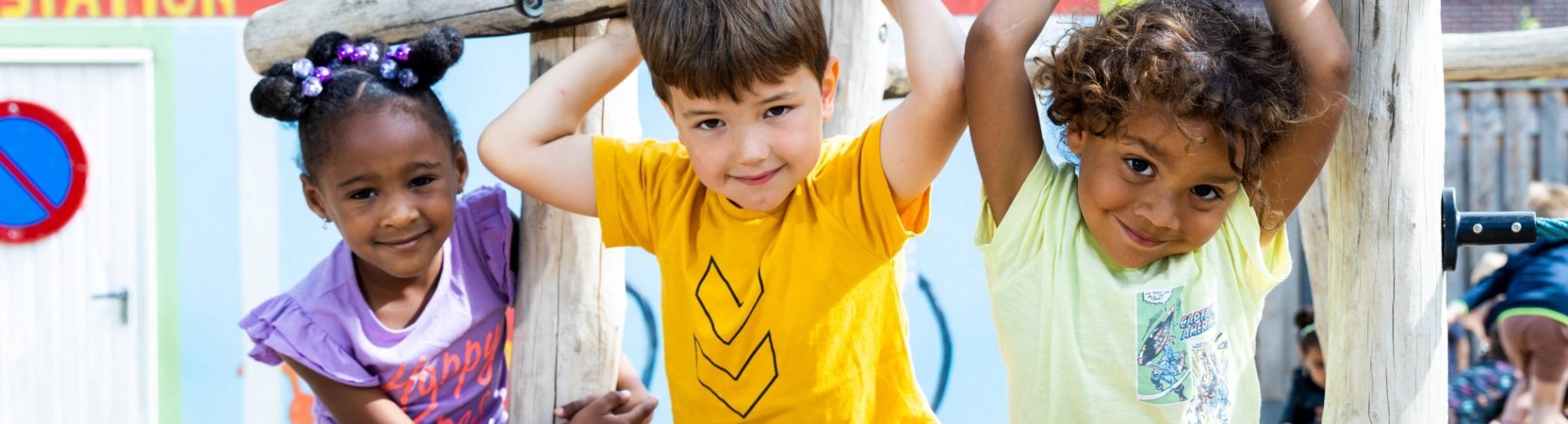 Drie kinderen spelen buiten en hangen aan het klimrek