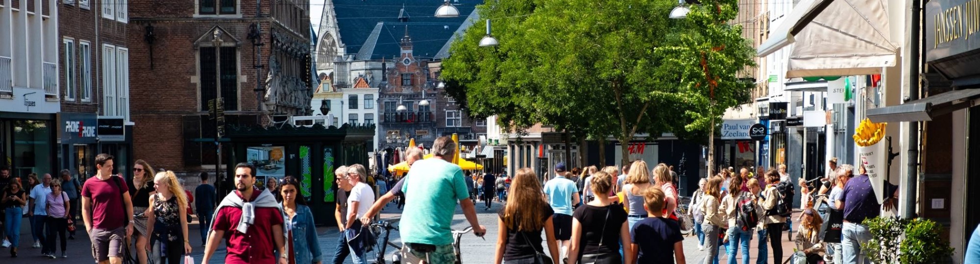 mensen in winkelstraat met kerk op achtergrond