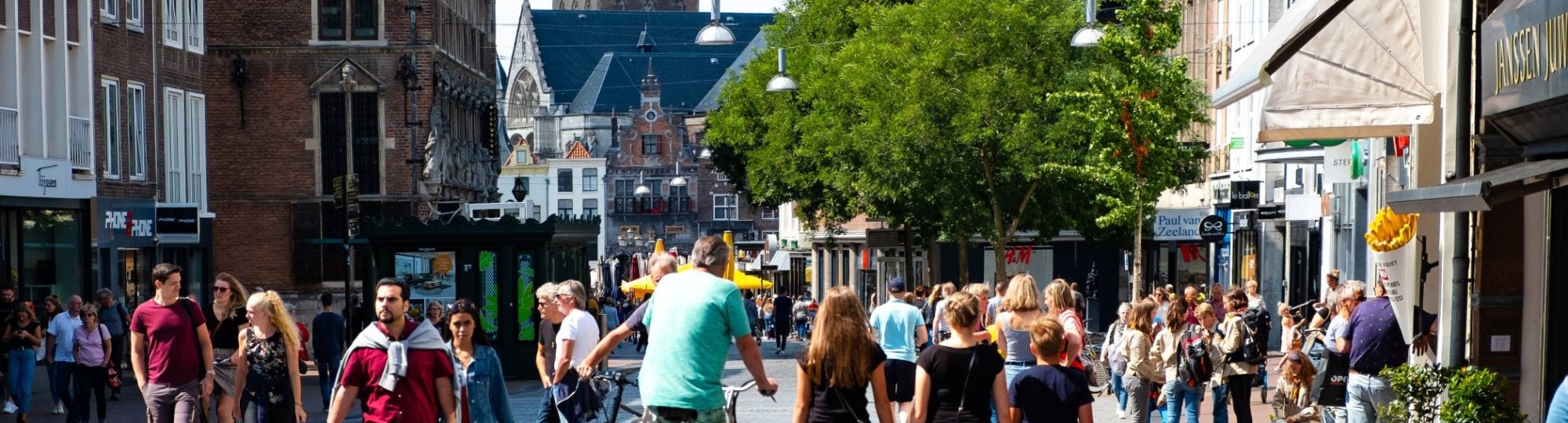 mensen in winkelstraat met kerk op achtergrond