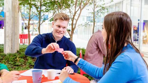 Student geeft een briefje aan een andere student