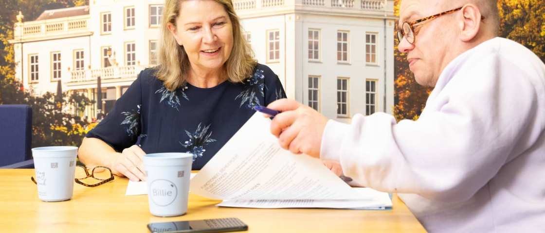 2 mensen aan tafel die naar een vel papier kijken