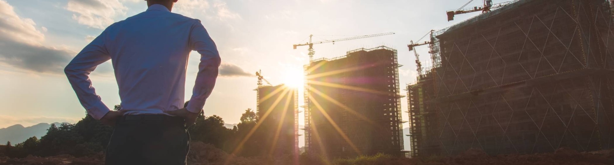 Opzichter bekijkt bouwplaats bij zonsopkomst