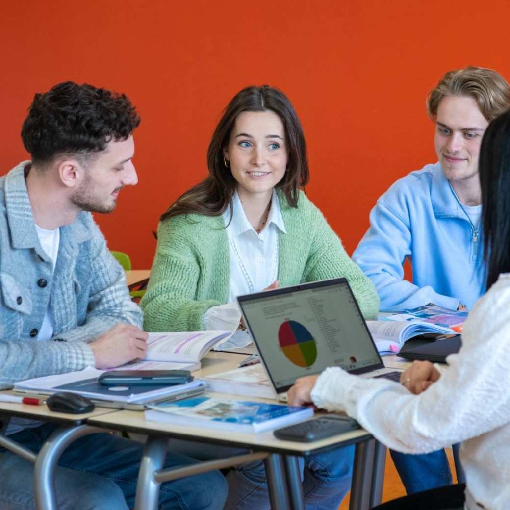 Docent geeft uitleg aan haar studenten over een groepsopdracht voor de opleiding Leraar Economie.