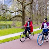 Diego and Nyugen riding their bikes on the bicycle road in the park.