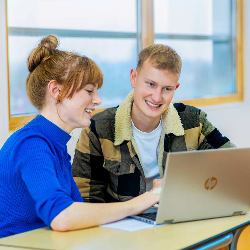 Twee vrouwenhanden typen op het toetsenbord van haar laptop.