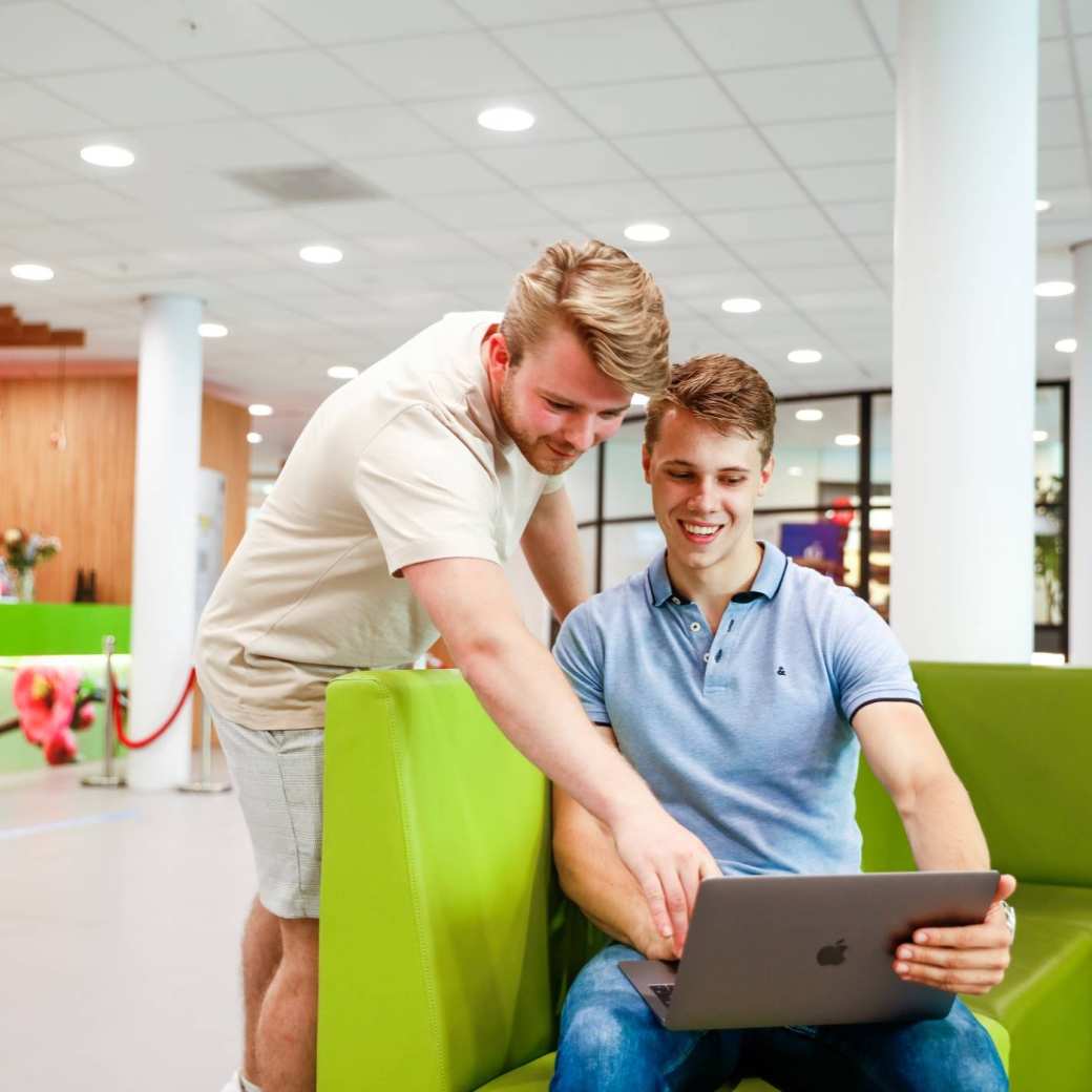 Studenten mannen overleg hal laptop