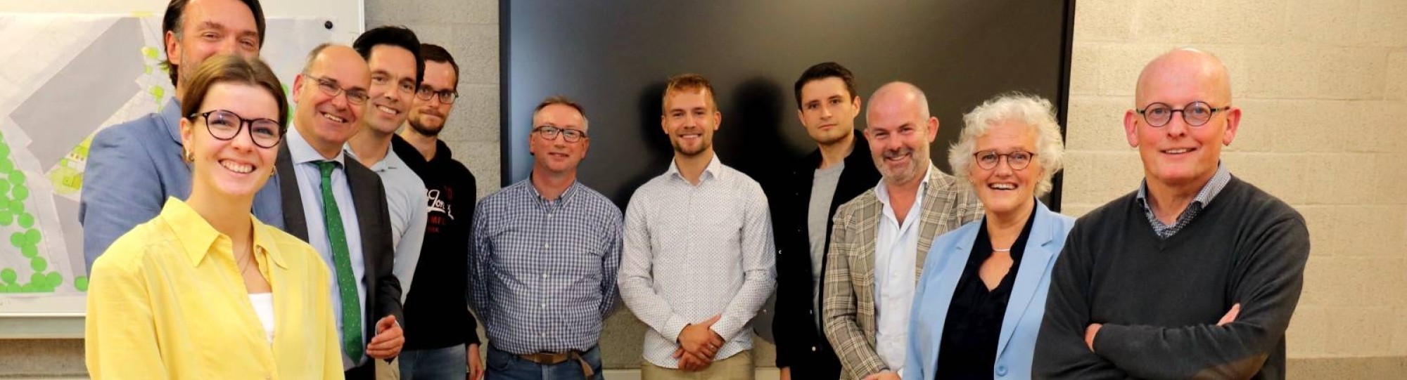 Drie studenten van de minor Circulaire Economie presenteren het plan Circular Square aan verschillende stakeholders. Er staan 11 mensen op de foto, die genomen is na het houden en bespreken van de presentatie. Lokaal op R31.