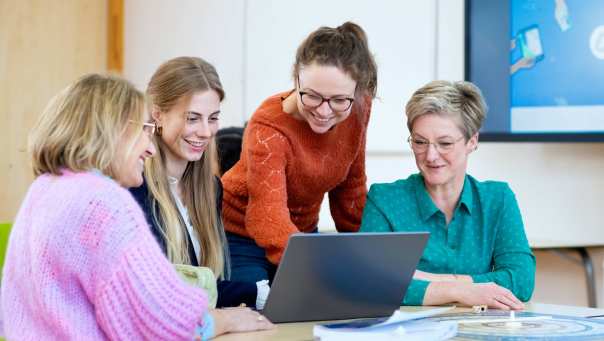 Vier studenten kijken samen naar het scherm (laptop). 