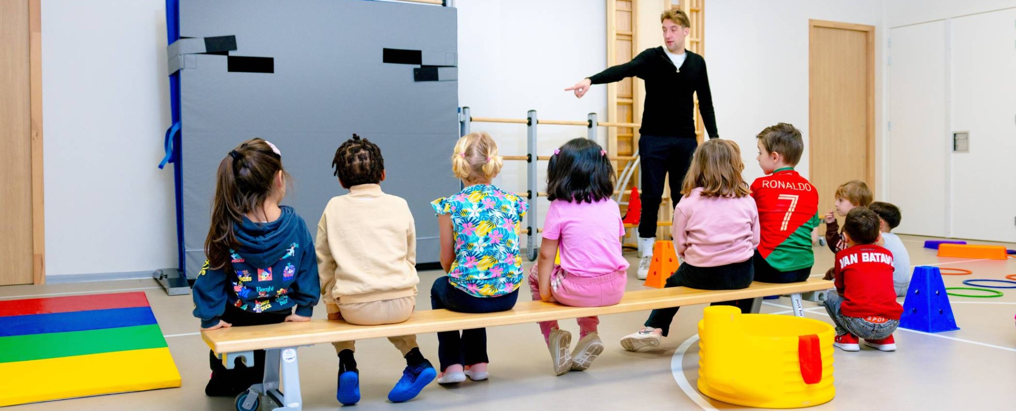 Juf begeleidt kinderen van de glijbaan in de buitenlucht.