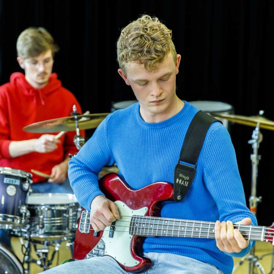 Een mannelijke student Social Work speelt gitaar tijdens een creatief vak op de Kapittelweg 33