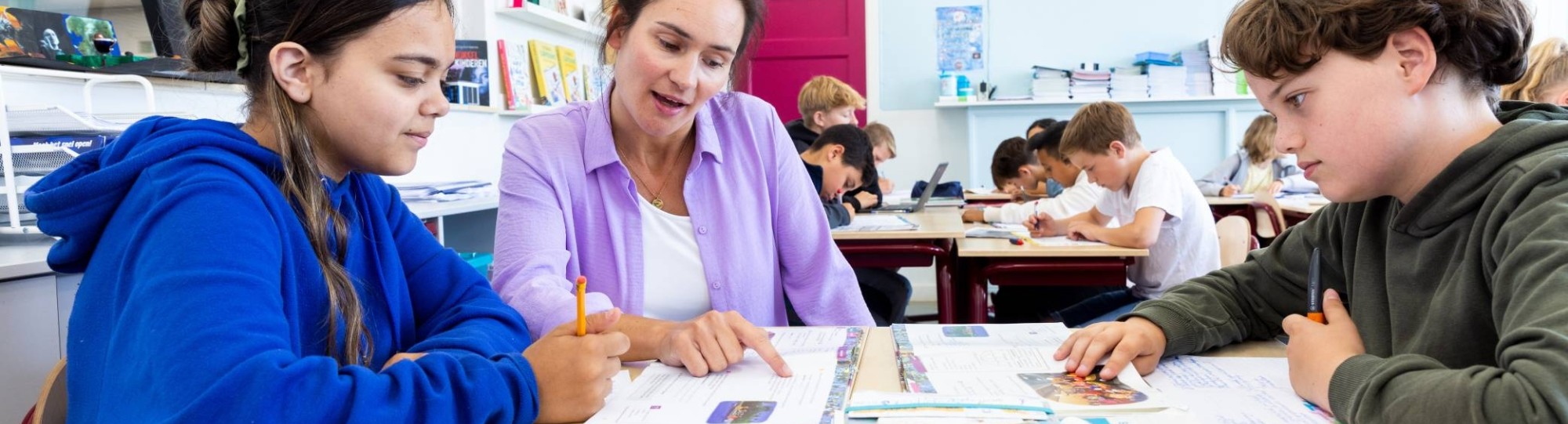 Docent Leonie van de opleiding leraar basisonderwijs aan tafel met leerlingen