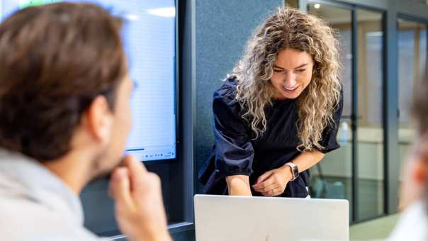 Deeltijd student Commerciële Economie aan het werk op laptop met medestudenten.