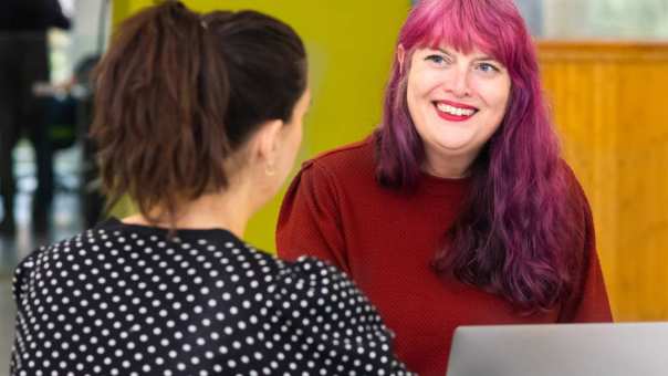 Twee studenten Leraar Engels zitten tegenover elkaar. Eentje heeft paars haar.
