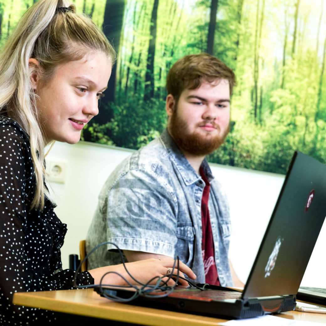 HAN Pabo Arnhem kijkt naar haar laptop. Medestudent kijkt toe.