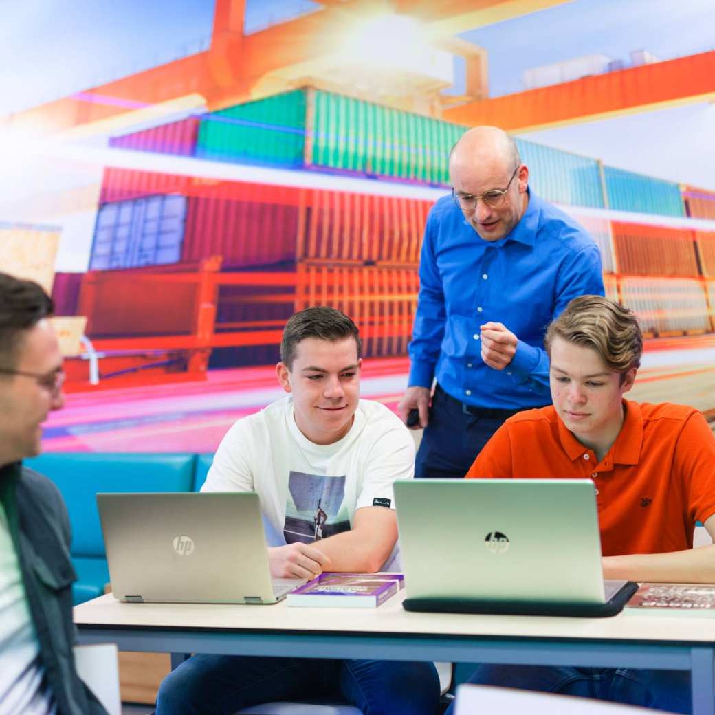 Logistics Management voltijd, LM, foto 7792, docent geeft uitleg aan tafel bij studenten in het lokaal