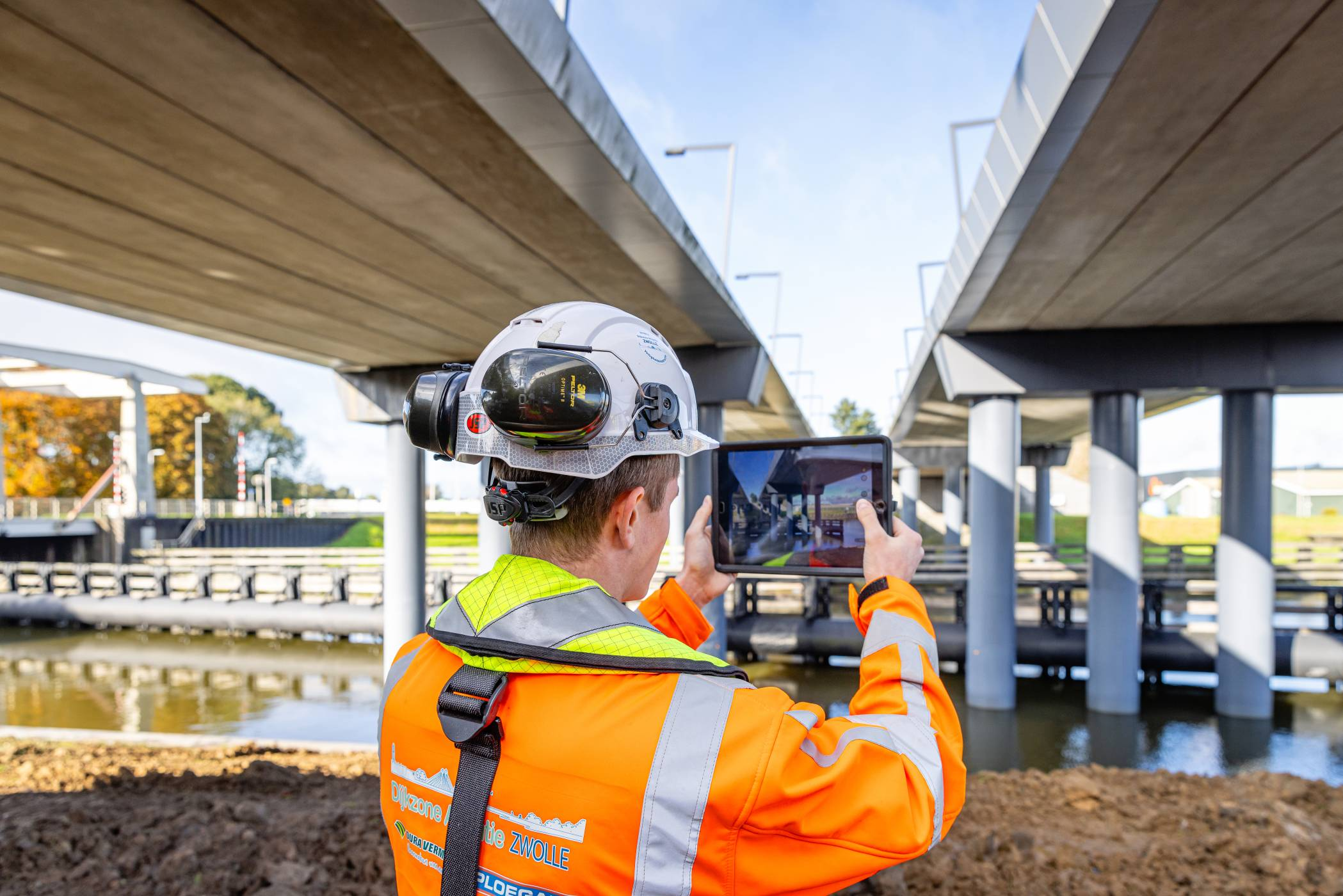 projectleider fotografeert met een tablet het werk aan een viaduct