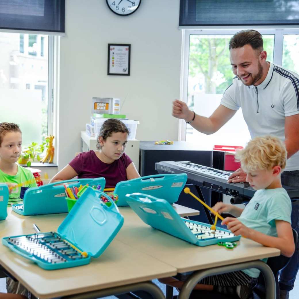 Leraar geeft muziekles aan kinderen op de basisschool.