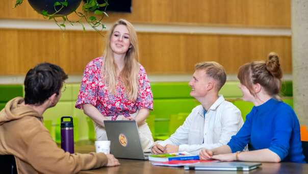 Vier studenten praten samen en lachen allemaal.