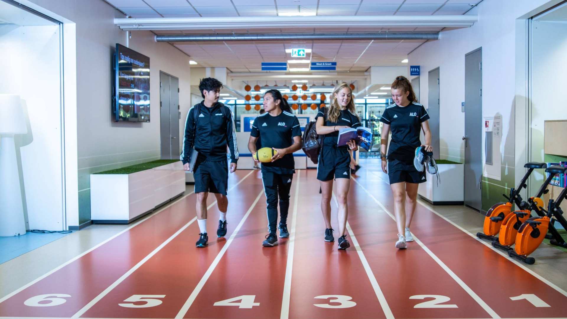 sportkunde en alo samen liggende foto studenten lopen over atletiekbaan binnen bij gymnasion veraf esteban selena carlijn randy 2022