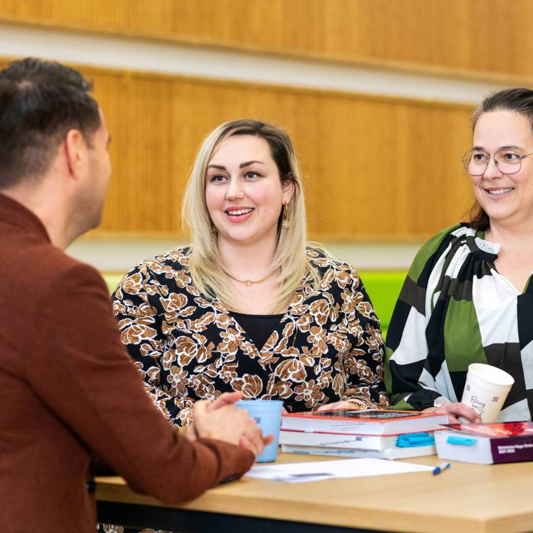 Twee vrouwen lachen tijdens een gesprek. 