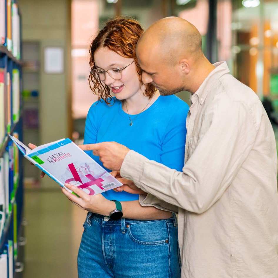 Twee wiskunde studenten bladeren door het lesboek, terwijl ze in het klaslokaal zitten.