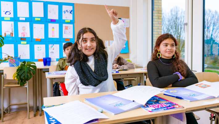 Groep 5,6,7 op de school Da Vince. De leerling steekt haar vinger op in de klas. 