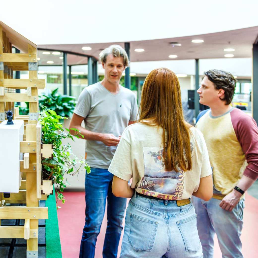 drie studenten exposeren hun werk op open up your talent aan een docent