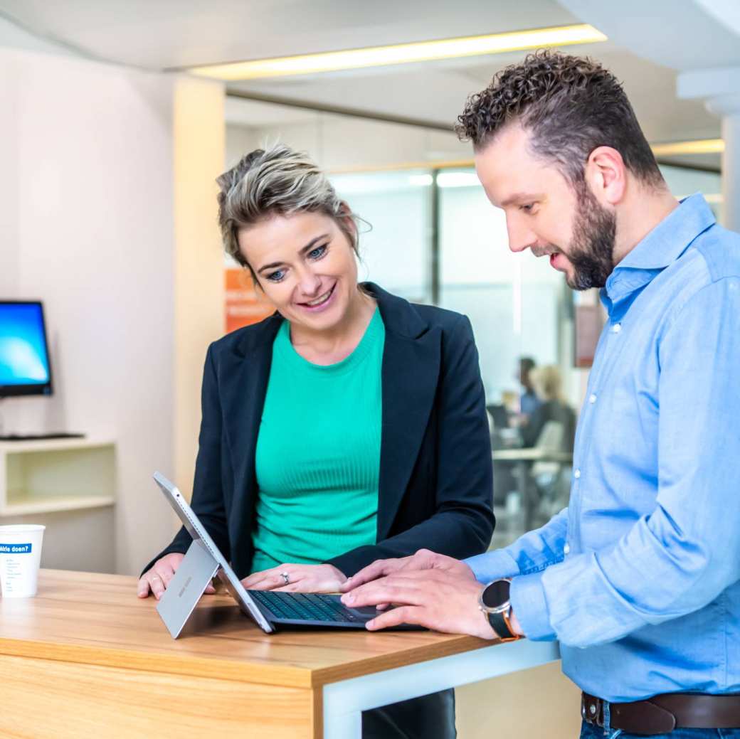 Twee master-studenten Business Sales overleggen aan een tafel.