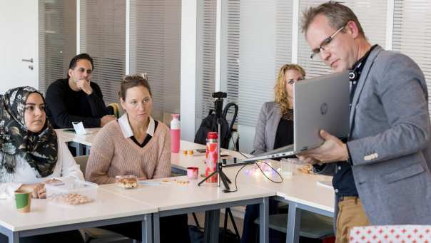 Man laat tijdens presentatie iets op zijn laptop zien aan zijn klasgenoten