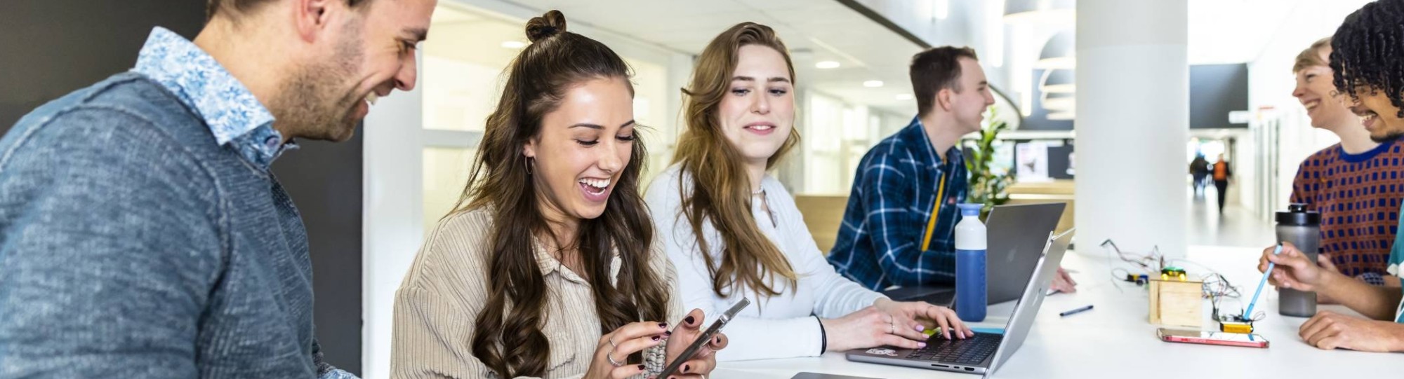 Studenten communicatie en multimedia design werken samen aan een opdracht in de lounge